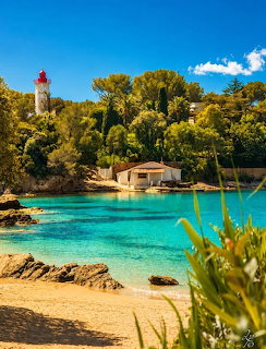 Turquoise cove with sandy beach, lighthouse, and green trees at Saint Raphaël, France