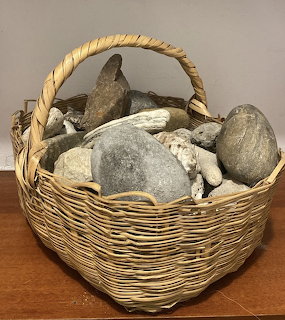 Wicker basket filled with assorted gray and beige rocks on a wooden table