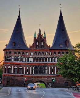 Holstentor gate in Lubeck with twin conical towers and brick facade at dusk