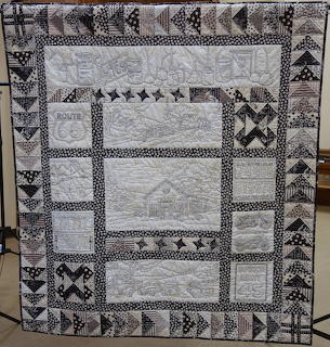 Vintage patchwork quilt with white embroidered panels and black and white patterned border