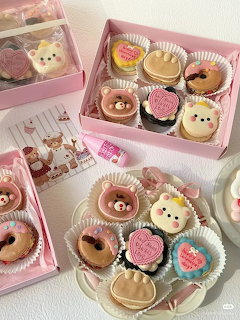Cute animal-shaped decorated cookies in pink gift boxes arranged on a white surface