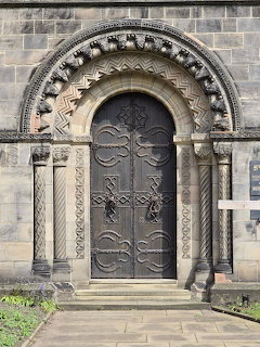 Ornate Norman arched doorway of a historic stone church in Stafford with carved stonework and decorative wooden doors