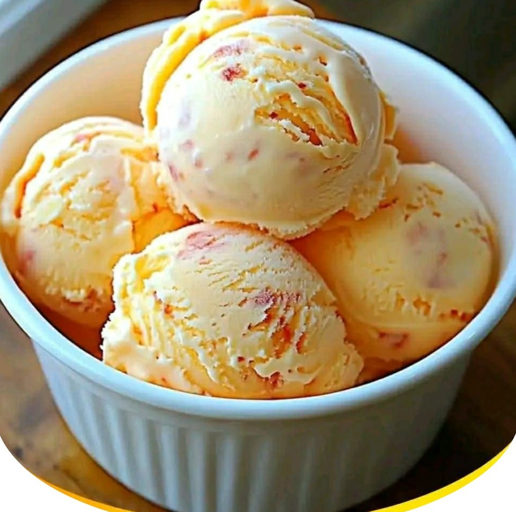 Scoops of peach ice cream with fruit swirls in a white ramekin