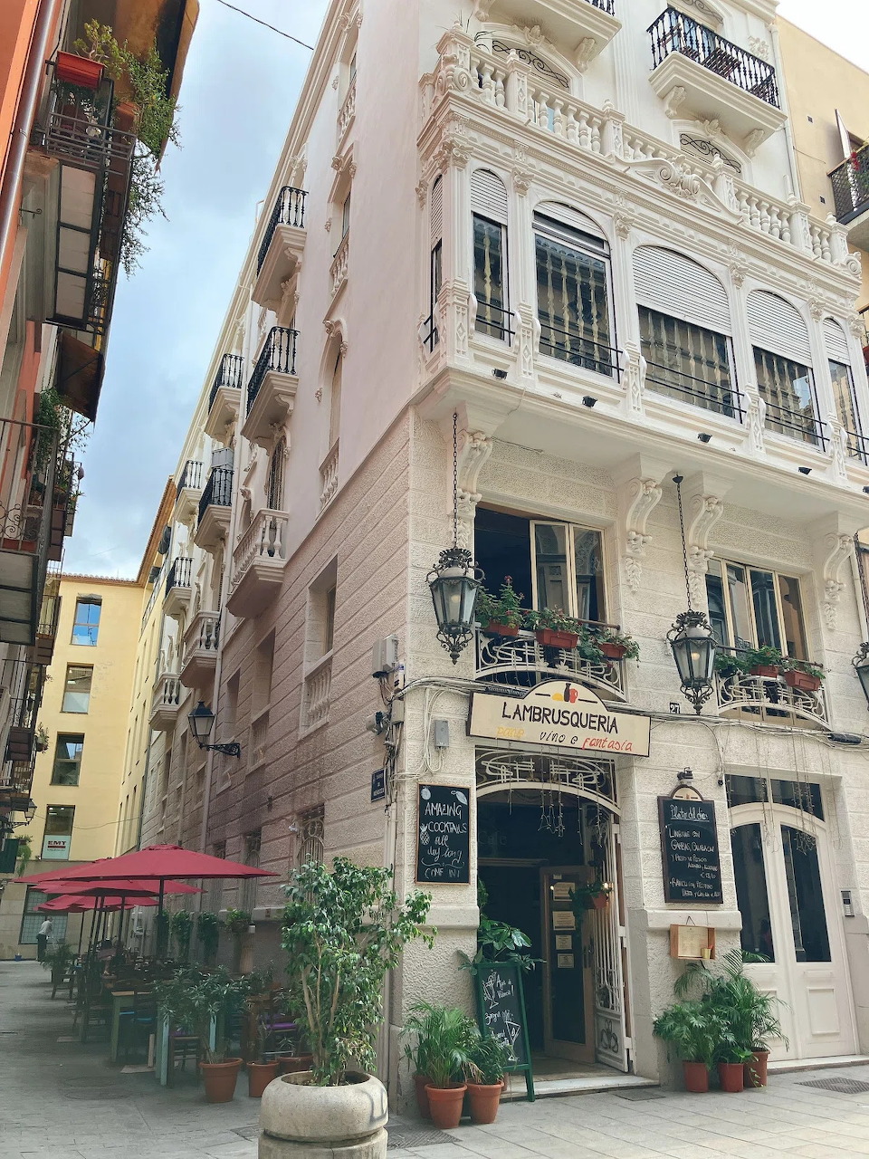 White corner building with balconies and street-level cafe in Valencia, Spain