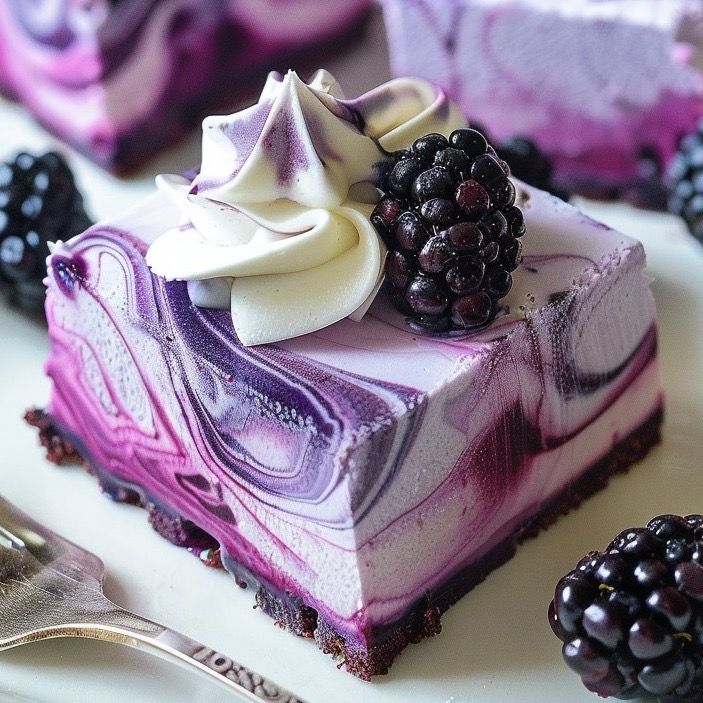 Purple marbled cheesecake slice with whipped cream and blackberries on a plate
