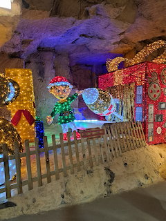 Illuminated elf and gingerbread house decorations inside a cave Christmas market with colorful lights