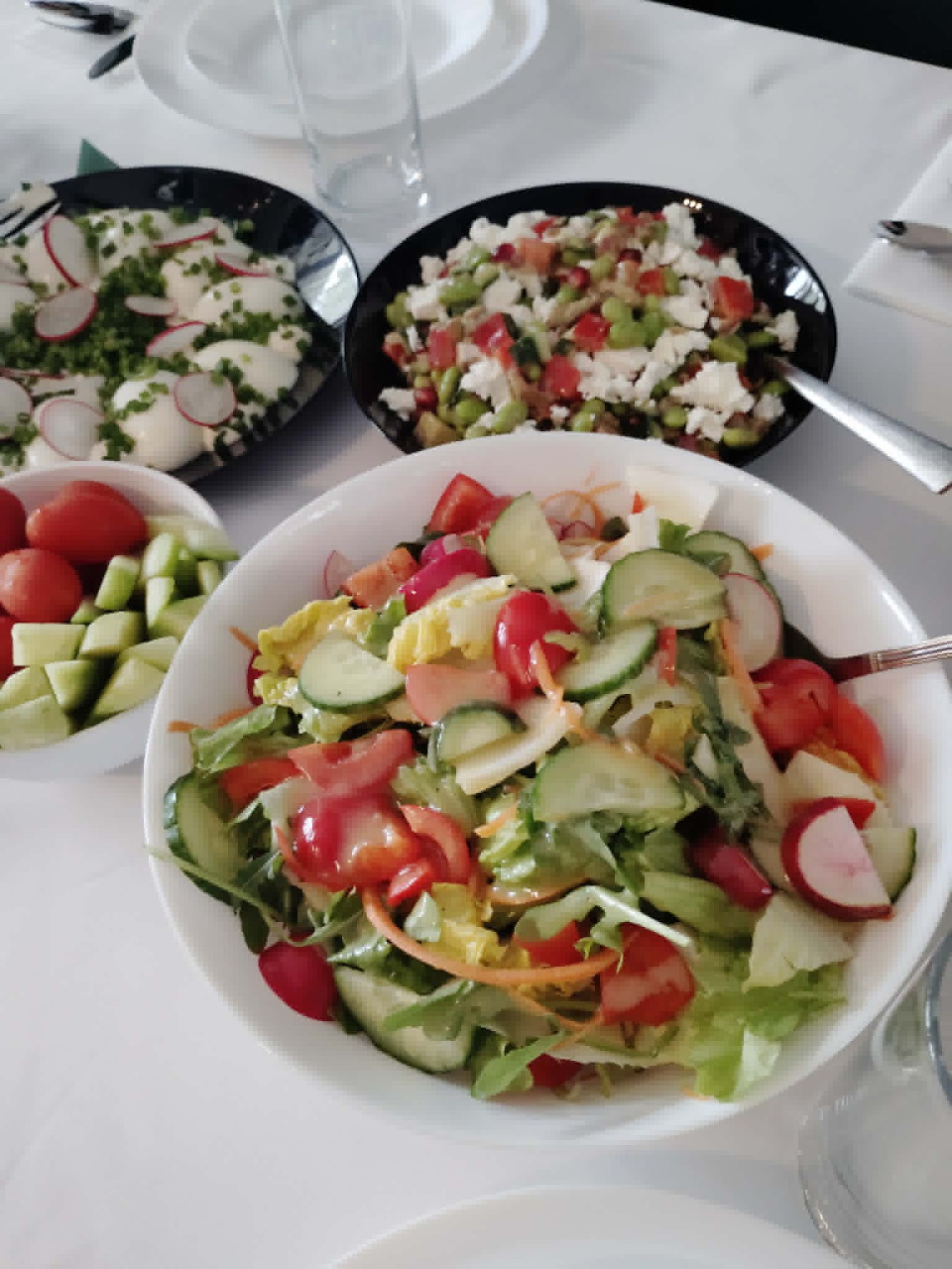 Three bowls of fresh mixed salad on a white table