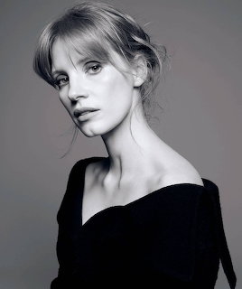Black and white portrait of a young woman with upswept hair wearing an off-shoulder black top