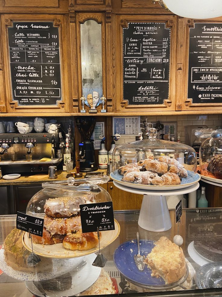 Cafe interior with pastry display cases, chalkboard menus, and wooden cabinets