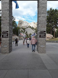 Mount Rushmore monument viewed through stone gateway entrance with visitors on walkway
