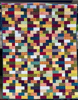 Colorful patchwork quilt with small square fabric patches in various colors arranged in a grid