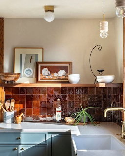 Modern kitchen with teal cabinets, brown tile backsplash, white farmhouse sink, and brass fixtures