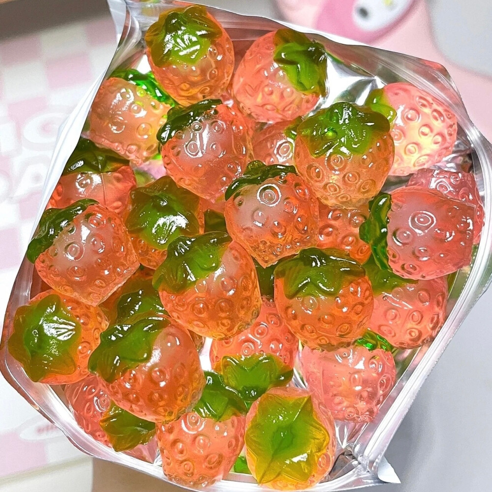 Clear container of pink and green strawberry-shaped gummy candies viewed from above