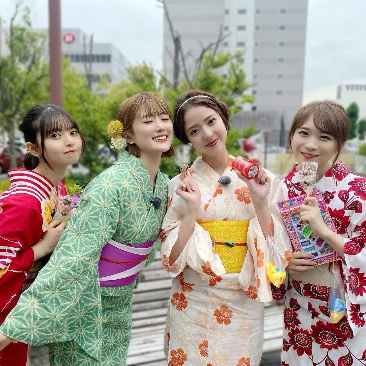 Four smiling women in colorful yukata kimonos posing together outdoors