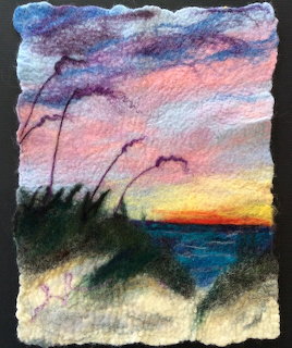 Needle felted art of a beach sunset with sea oats, colorful sky, and ocean horizon