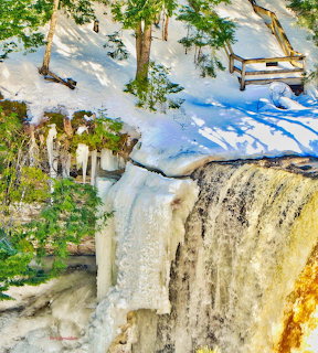 Aerial view of frozen waterfall with snow and evergreen trees