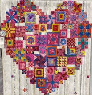 Heart-shaped patchwork quilt with colorful geometric fabric squares on white wood