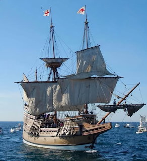 Historic tall sailing ship with white sails on a blue sea under a clear sky