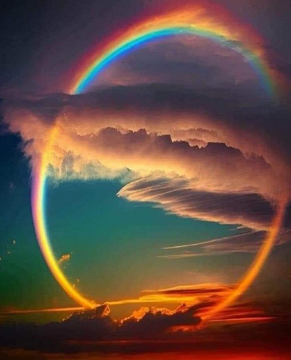 Full circular rainbow forming a complete ring against dramatic sunset clouds