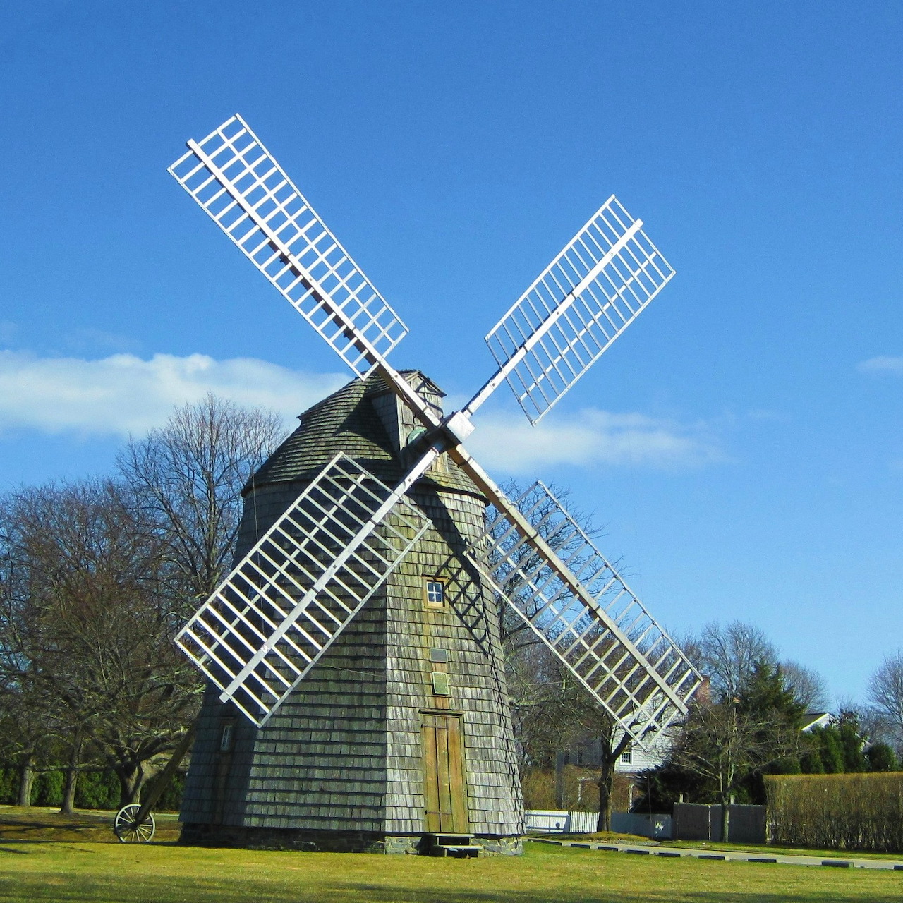 Wooden windmill in a field beneath a clear blue sky