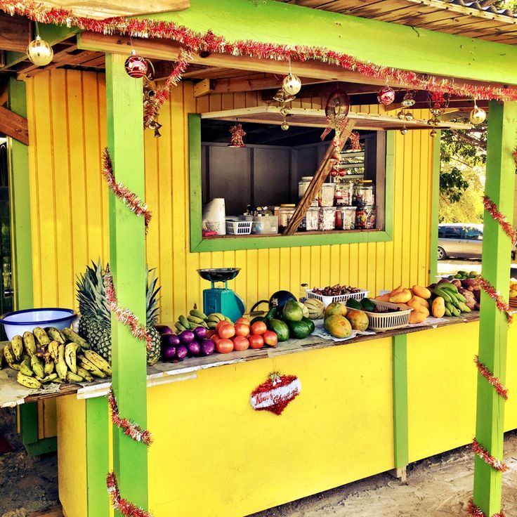 Bright yellow fruit stand displaying bananas, pineapples, melons, and assorted fresh produce