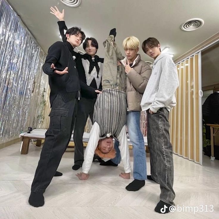 Five young men posing indoors, including one upside down on the floor