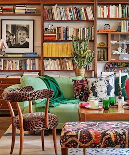 Cozy living room with bookshelves, green sofa, patterned chair, and coffee table