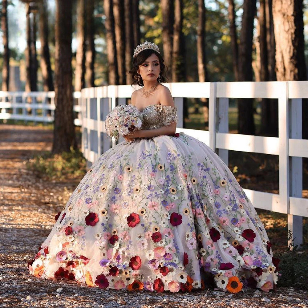 Young woman in a floral quinceanera ball gown standing by a white fence in a wooded area