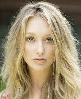 Portrait of a young blonde woman with blue eyes and tousled hair looking at camera