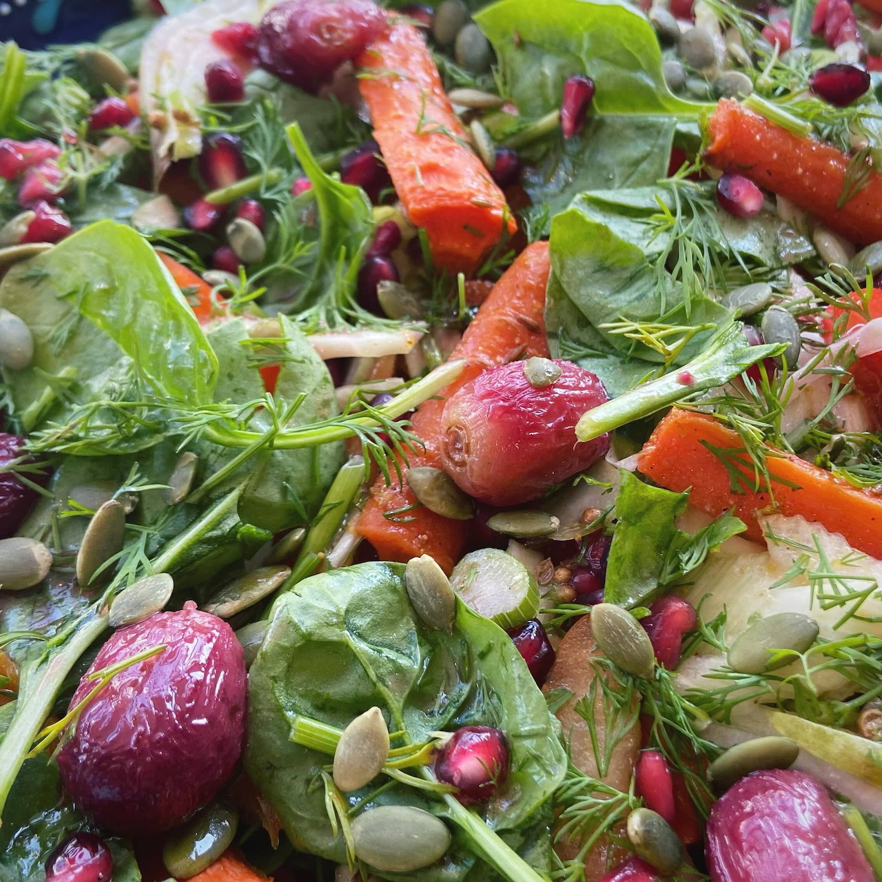 Close-up of a fresh salad with spinach, radishes, carrots, seeds, and pomegranate