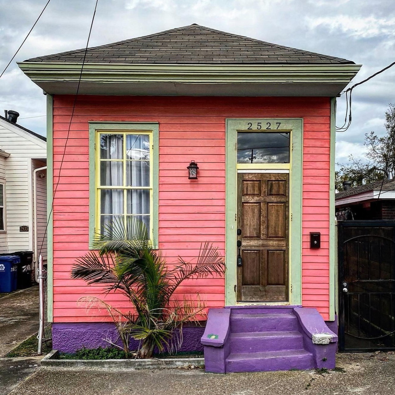 Small pink house facade with yellow-trimmed windows, brown door, and purple steps