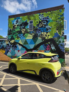 Colorful graffiti mural on building with yellow car parked in front