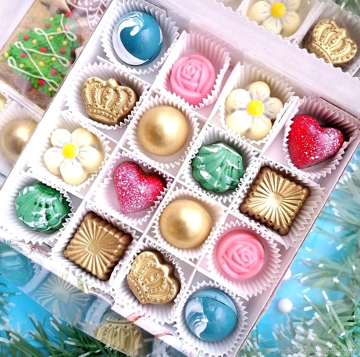 Box of assorted decorated chocolates in various colors and shapes including roses, flowers, and gold spheres