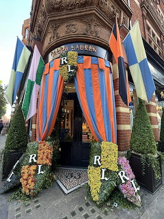 Brick Chelsea storefront with striped drapes, flowers, and colorful flags around the doorway