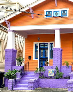 Bright orange house with purple porch, columns, steps and blue front door