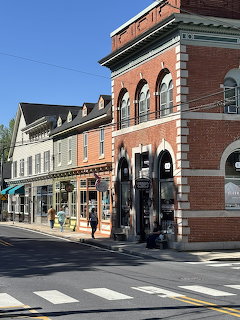 Historic Main Street with brick and white storefront buildings, shops, and crosswalk under blue sky