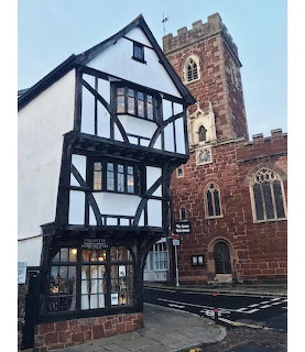Timber-framed Tudor-style house on a street corner with leaded windows and dark wooden beams.