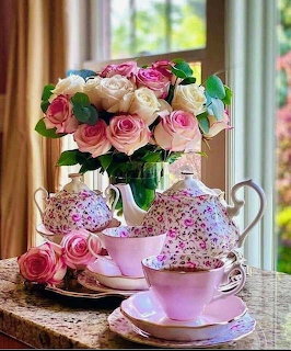 Floral teapot and pink teacups with a bouquet of pink and white roses by a window