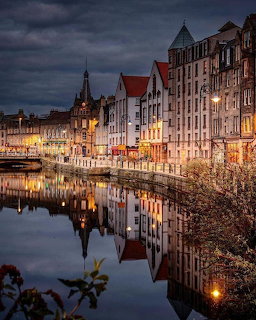Historic Leith waterfront buildings reflected in water at dusk with dramatic cloudy sky