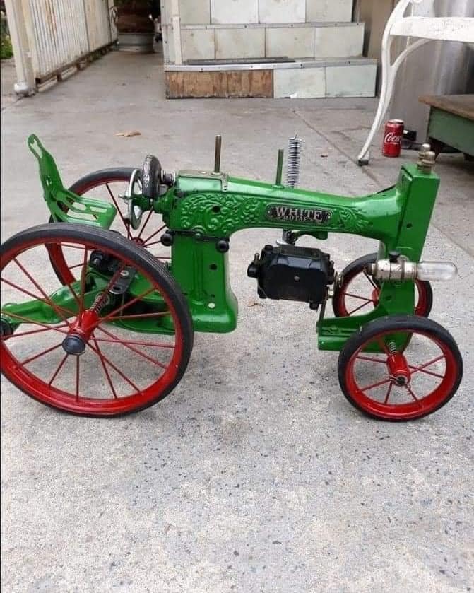 Green vintage toy tractor with red spoke wheels on concrete ground