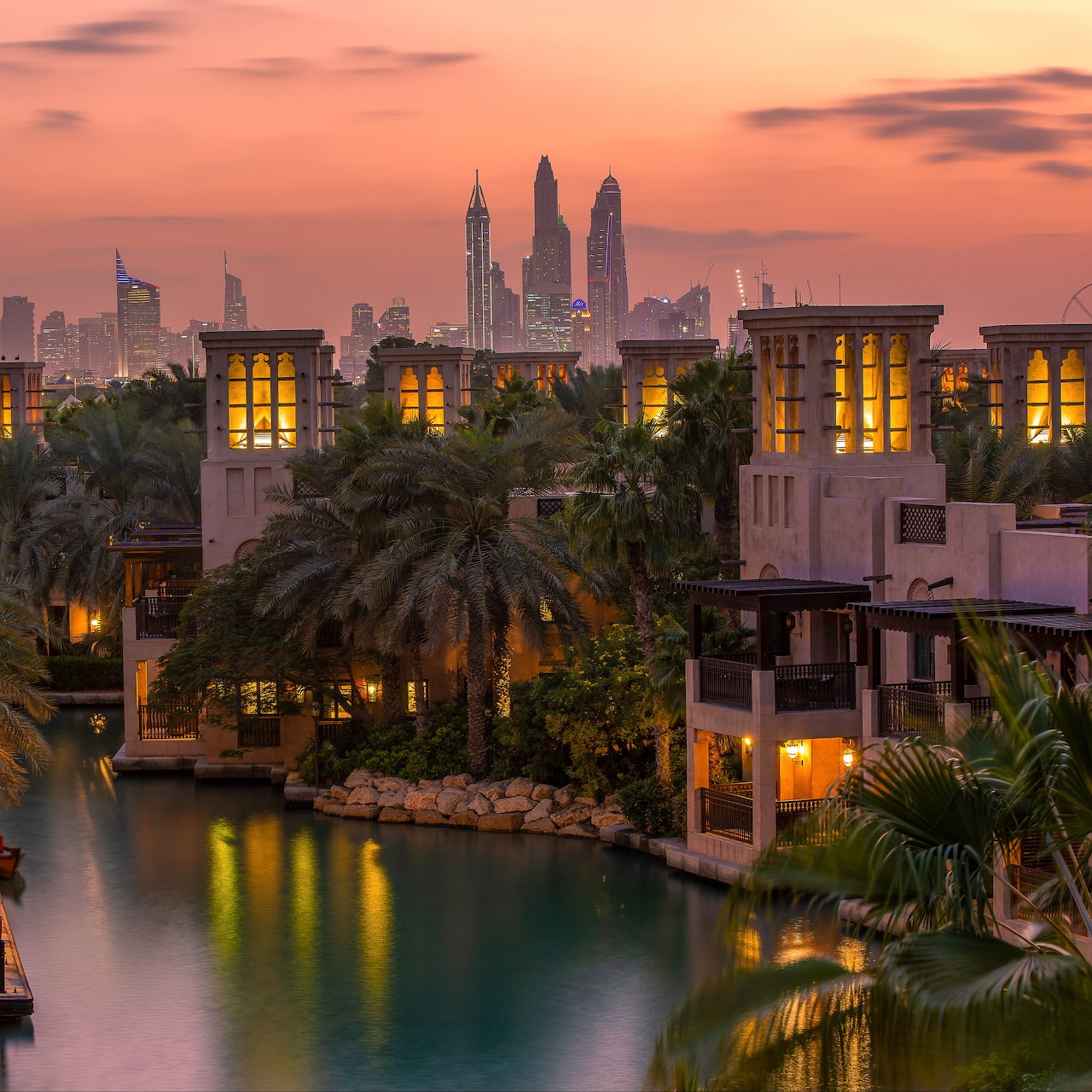 Twilight view of Souk Madinat Dubai with canal, palm trees, lit buildings, and skyline