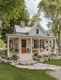Small white cottage with covered porch surrounded by trees and stone landscaping