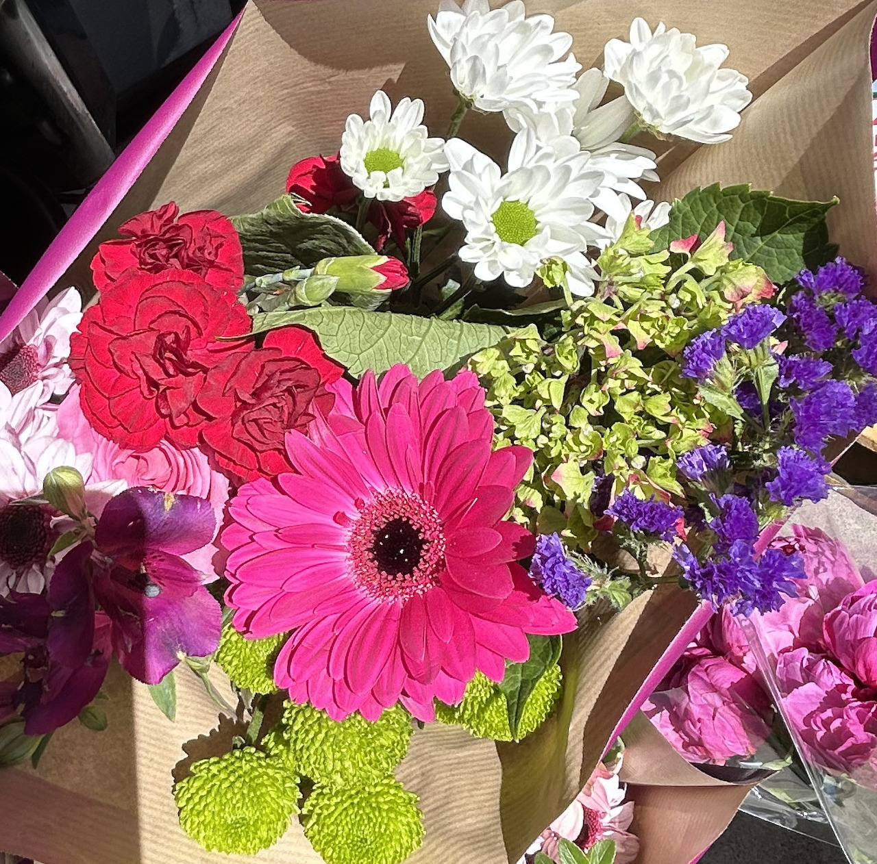 Bouquet of pink, white, red, and purple flowers wrapped in brown paper
