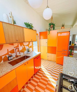 Bright orange retro kitchen with colorful cabinets, patterned backsplash, and striped floor tiles