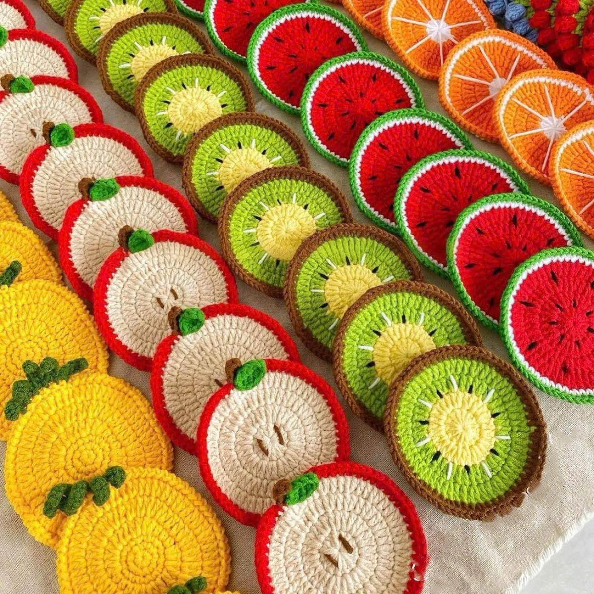 Colorful crocheted coasters shaped like fruit slices including kiwi, watermelon, orange, lemon, and apple