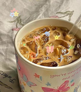 Iced coffee with butterfly sprinkles in a cream-colored mug decorated with butterflies and text