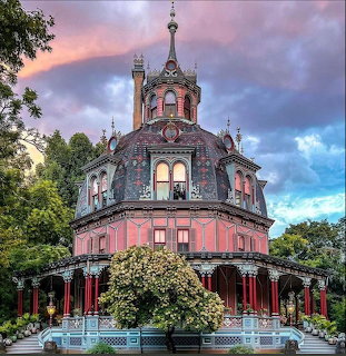 Pink octagonal Victorian mansion with ornate cupola at sunset