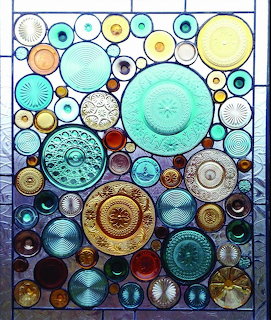 Stained glass window artwork composed of recycled glass plates and dishes in various colors and circular patterns