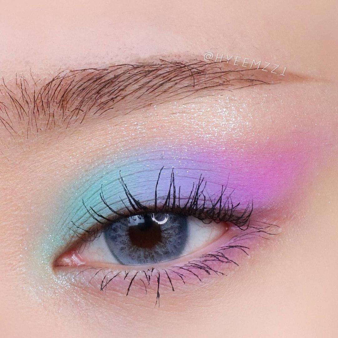 Close-up of a blue eye with pastel rainbow eyeshadow and long lashes