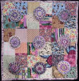 Colorful patchwork quilt with floral patterns and circular fabric designs in varied colors
